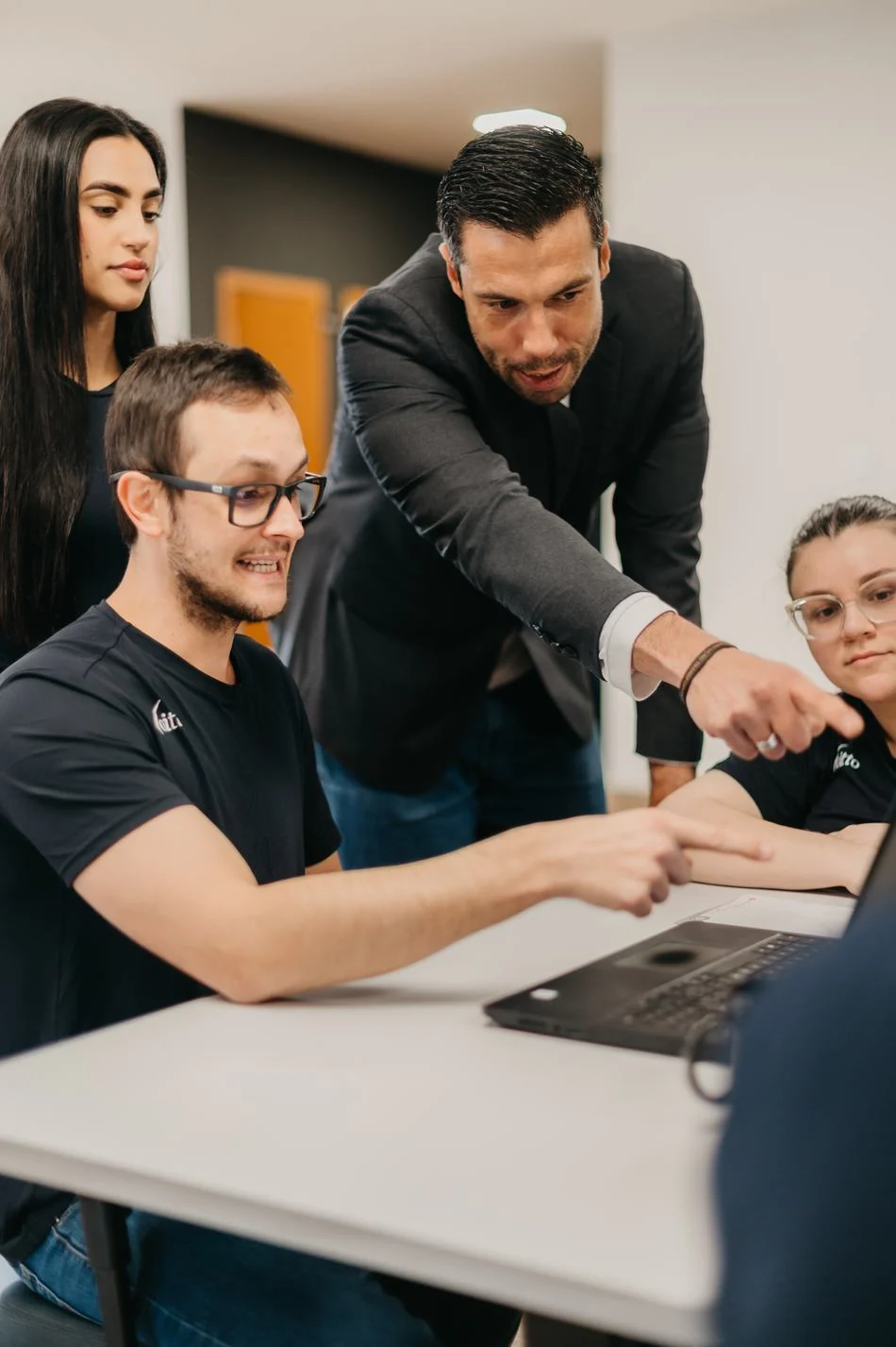 Gestor orientando de perto um colaborador em frente ao computador
