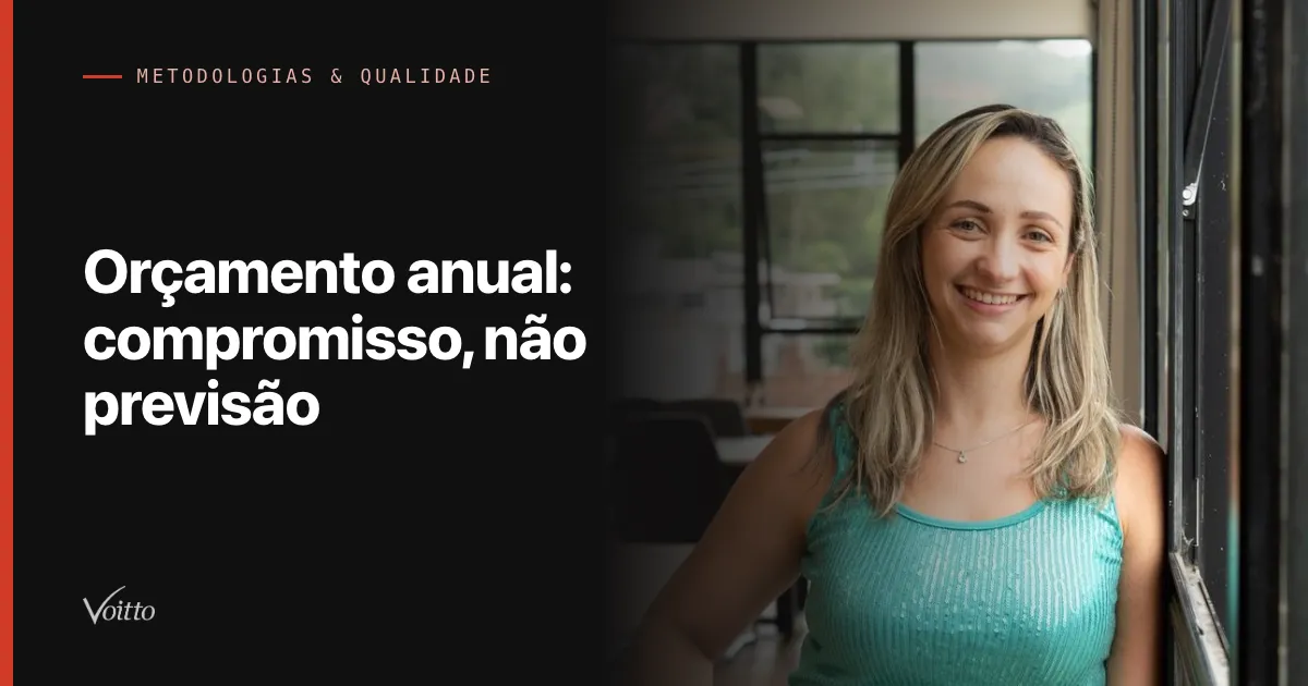 Colaboradora da Voitto sorrindo junto à janela do escritório, com as vidraças ao fundo, com o texto Orçamento anual: compromisso, não previsão sobre fundo escuro à esquerda