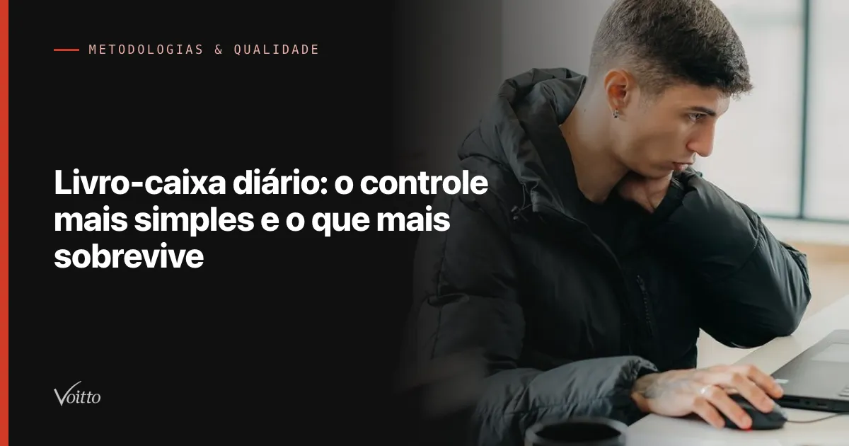 Colaborador da Voitto de casaco escuro trabalhando concentrado no computador, visto de perfil na mesa do escritório, com o texto Livro-caixa diário: o controle mais simples e o que mais sobrevive sobre fundo escuro à esquerda