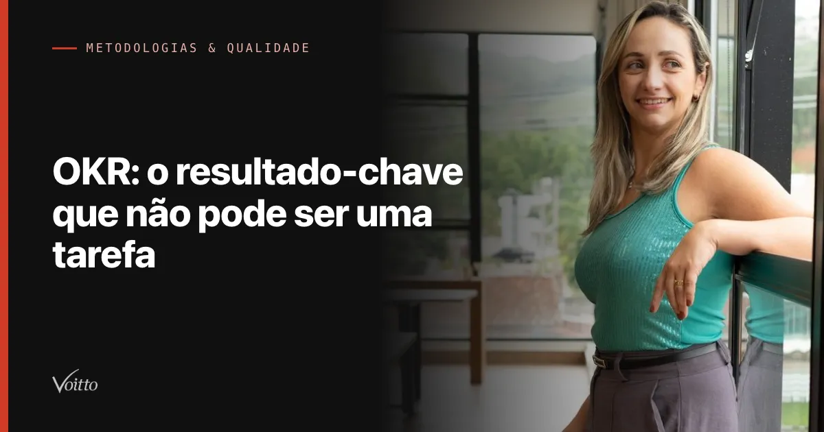 Colaboradora da Voitto de blusa verde-água em pé no escritório, apoiada em uma cadeira e sorrindo para a câmera, com o texto OKR: o resultado-chave que não pode ser uma tarefa sobre fundo escuro à esquerda