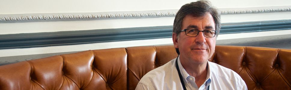 Michael Pachter em um sofa marrom. Michael Pachter em um sofa marrom.